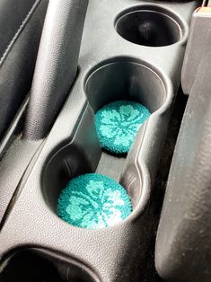 two blue cupcakes sitting in the center console of a car