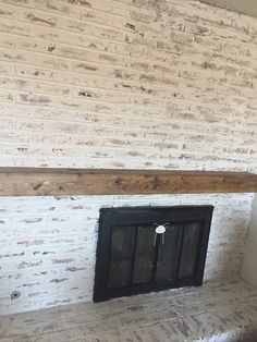 an empty room with a brick fireplace and white painted bricks on the wall behind it