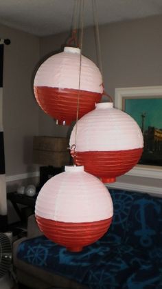 three red and white paper lanterns hanging from the ceiling in a living room with a blue couch