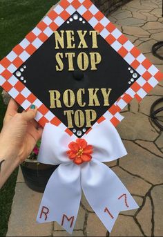 someone is holding up a graduation cap that says next stop rocky top with an orange flower on it