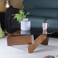 a coffee table with a glass top and wooden legs in front of a blue couch