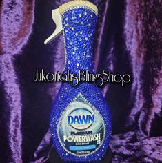 a blue bottle that is on top of a purple table cloth with the words dawn in front of it