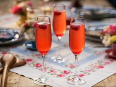 two glasses of wine sitting on top of a table next to plates and utensils