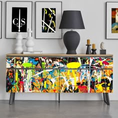 an abstract painting is on the sideboard next to two lamps