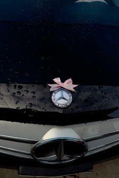 the front end of a mercedes car with a pink bow on it's emblem