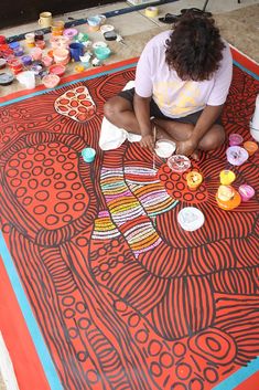 a woman is sitting on the floor painting