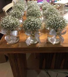 four glass vases with baby's breath flowers in them on a wooden table