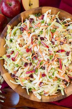 a wooden bowl filled with coleslaw slaw next to apples and other fruit