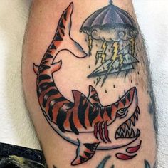 a man with a tattoo on his leg that has a shark and an umbrella in it