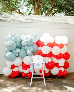 a chair sitting in front of a bunch of balloons on the side of a building