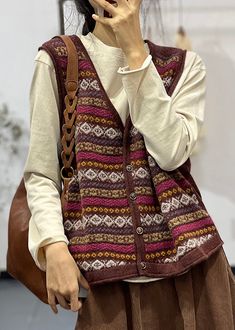 a woman talking on her cell phone while wearing a knitted sweater and brown skirt