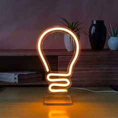 a light that is sitting on top of a wooden table in front of a potted plant