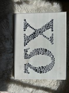 a white canvas with black and silver beads on it