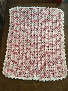 a crocheted blanket sitting on top of a wooden table next to a box