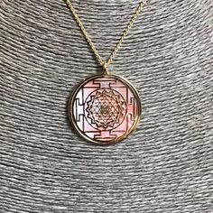 "Sri Yantra pendant in 24 carat gold on 925 silver and rose natural mother of pearl backdrop. It's one of the most powerful symbol in sacred geometry, belonging both to Induism and Buddhism traditions. It has a complex structure made of nine interlocking triangles: four of them, looking upside, show male power and Shiva, five of them, looking down side, express a female Energy and her Goddes Shakti. These 43 triangles represent the cosmos and the human body, they surround a point known as bindu, Hallmarked Rose Gold Symbolic Necklace, Pink Gold Necklace With Polished Finish For Gift, Spiritual Rose Gold Locket Necklace, Pink Spiritual Round Pendant Jewelry, Spiritual Pink Round Pendant Jewelry, Pink Amulet Necklace For Gift, Pink Medallion Jewelry As A Gift, Pink Medallion Necklace For Gifting, Pink Medallion Jewelry For Gifts