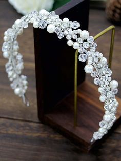 the bride's headpiece is adorned with pearls and crystal beads, which are attached to a wooden stand