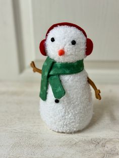 a white snowman with a red hat and green scarf