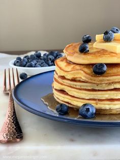 a stack of pancakes topped with blueberries and butter