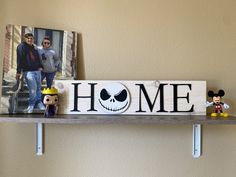 a wooden sign with the word home on it next to two small figurines