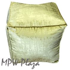 a gold square pillow sitting on top of a white floor