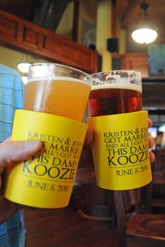 two people holding up beer glasses with names on them