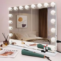 a vanity mirror sitting on top of a white table next to a hair dryer