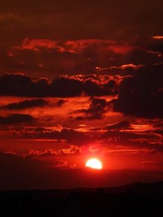 the sun is setting behind some clouds in the sky with red and orange colors on it