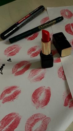 lipstick and pencils sitting on top of a white tablecloth with red lips drawn on it