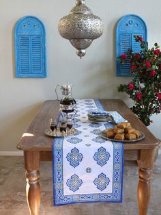 a wooden table topped with plates and food next to blue shuttered window panes