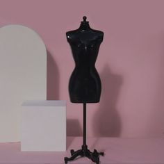 a black mannequin sitting on top of a table next to a white box