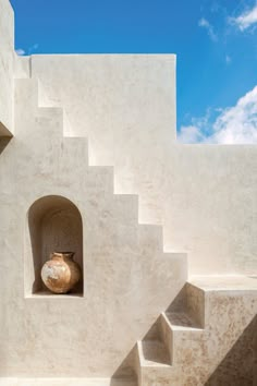 a white building with steps leading up to it and a vase sitting in the window