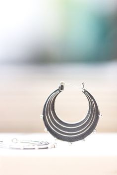 "Evocative of raindrops striking a pool of water, circles radiating outward from the point of impact and smaller droplets becoming airborne. These earrings are made completely of sterling silver, right down to the ear wires which are hinged and connect in a catch on the other side. The line and ball design is repeated on both sides of each earring. Each hoop measures approximately 1.25\" in diameter. The hoops have been given a patina to darken them and then tumbled in steel shot to give them a Modern Nickel-free Drop Hoop Earrings, Nickel-free Metal Drop Hoop Earrings, Everyday Drop Hoop Earrings, Everyday Metal Drop Hoop Earrings, Metal Drop Hoop Earrings With Ear Wire, Unique Dangle Hoop Earrings For Everyday, Unique Hypoallergenic Hoop Jewelry, Unique Small Hoop Hypoallergenic Earrings, Round Teardrop Earrings For Everyday