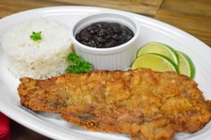 a white plate topped with fish and rice next to a bowl of black bean sauce