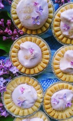 several desserts with frosting on top of them and purple flowers in the background