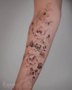 a woman's arm with flowers on it, and the tattoo is black and white