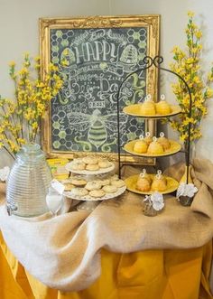 a table topped with cakes and pastries next to a chalkboard