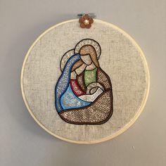 a cross stitched in to a hoop with an image of a mother and child