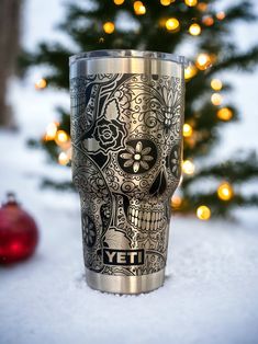 a metal cup sitting in the snow next to a christmas tree