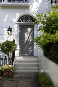 a white house with a gray front door and steps leading up to the entryway