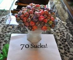 a vase filled with lots of candy sitting on top of a table next to a sign that says 70 sucks