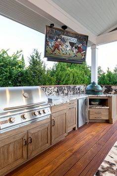 an outdoor kitchen with wood floors and grilling area on the side of the house