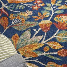 a close up view of a blue rug with orange and green floral designs on it