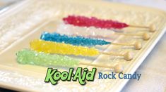 several skewers of colorful candy on a plate with the words kool aid rock candy