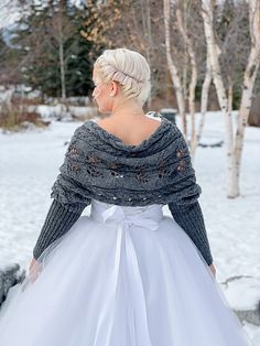 a woman in a white dress is standing in the snow with her back to the camera