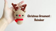 a hand holding a small crocheted christmas ornament with reindeer antlers on it