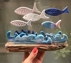 a hand holding a small tray with fish on it and waves in the ocean below