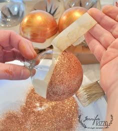 someone is decorating a christmas ornament with gold glitter and a paintbrush