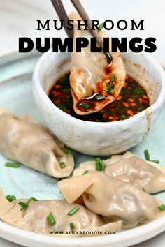 some dumplings are on a plate with chopsticks in it and sauce is in the bowl