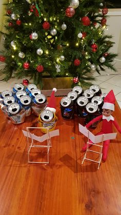 two elfs are sitting in front of a christmas tree with beer cans on the floor