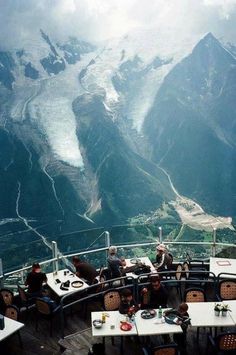 people are sitting at tables on top of a mountain